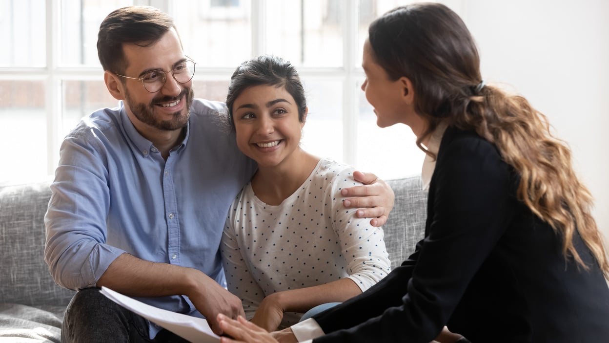 Happy family couple clients meeting professional real estate agent.