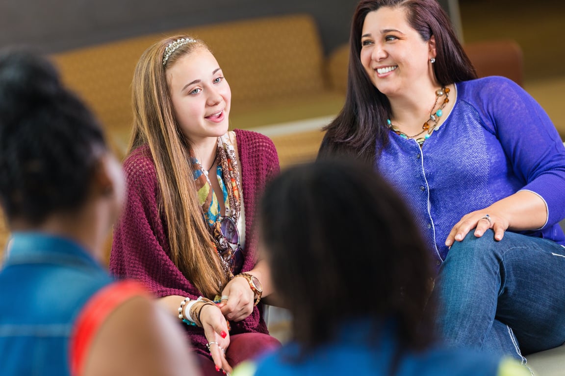 Teenage girl talking to group while in a parent meeting